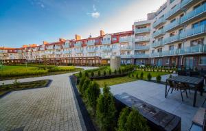 a large apartment building with a courtyard with a bench at Wyspa Uznam - Rondo Róży Wiatrów in Świnoujście