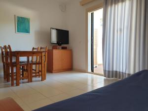 sala de estar con TV, mesa y sillas en Apartamentos Piscis, en Cala Blanca