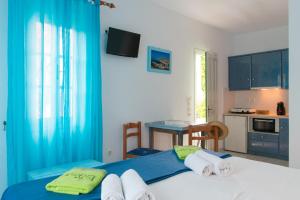 a bedroom with a bed with blue curtains and a kitchen at Edem Hotel in Platis Gialos