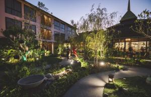 a person walking through a garden in front of a building at Spice House Chiang Mai in Chiang Mai