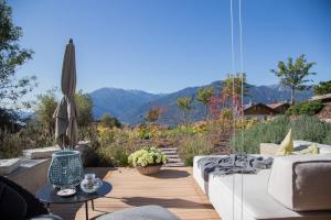 eine Terrasse mit einem Sofa, einem Sonnenschirm und einem Tisch in der Unterkunft Villa Grüntaler by Hotel Schönblick in Rodeneck