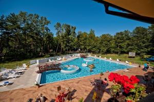a large swimming pool with people sitting in chairs around it at Ośrodek Zacisze in Rozewie