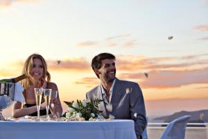 un uomo e una donna seduti a un tavolo con bicchieri da vino di Thermes Luxury Villas And Spa a Megalochori