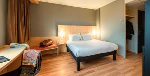 カンペルレにあるibis Quimperleの大きなベッドとデスクが備わるホテルルームです。