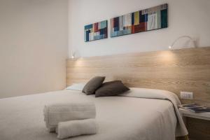 a bedroom with a white bed with a wooden headboard at Hotel Albània in Otranto