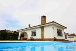 una casa con piscina frente a ella en Villas Aloha Valdelagrana, en El Puerto de Santa María