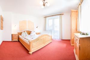 a bedroom with a wooden bed and a red carpet at Brollerhof in Neustift im Stubaital +46 photos