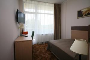 a hotel room with a bed, television and a desk at Medical SPA "Eglės sanatorija" Birštonas in Birštonas