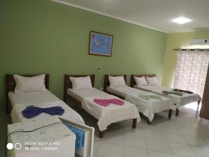 three beds in a room with green walls at Suítes Ubatuba Praia da Lagoinha in Ubatuba