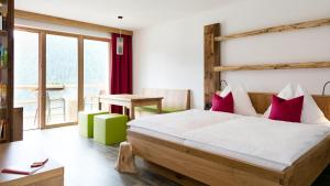 a bedroom with a large bed and a table at Almfamilyhotel Scherer in Obertilliach