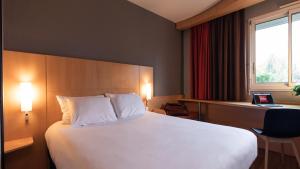 a hotel room with a large bed and a desk at ibis Quimperle in Quimperlé