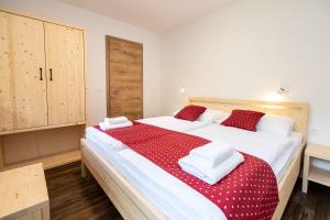 1 dormitorio con 1 cama grande con sábanas rojas y blancas en Bohinj Apartments Goldhorn Kingdom, en Bohinj