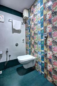 a bathroom with a toilet and a tiled wall at Hotel City View in Navi Mumbai