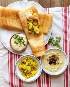a plate of food with bread and two bowls of dips at Hotel Crystal Luxury Inn- Bandra in Mumbai