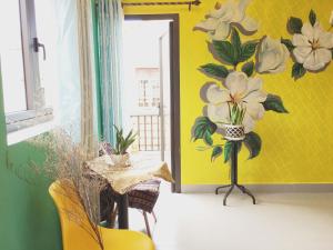 a room with a yellow wall with flowers on it at Longan Homestay in Hoi An