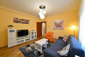 ein Wohnzimmer mit einem blauen Sofa und einem TV in der Unterkunft Apartment Ana in Zagreb