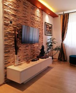 a living room with a tv on a brick wall at Oasis felix apartment in Belgrade