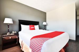 a bedroom with a large bed with a red and white blanket at OYO Hotel Shreveport Airport North in Shreveport