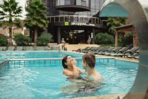 un hombre y una mujer en una piscina en Экодом Адлер, hotels&SPA, en Adler