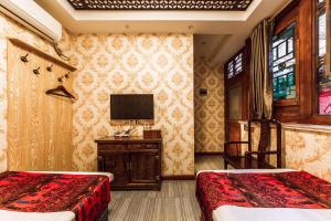 a bedroom with two beds and a tv on the wall at Pingyao Hongyuyuan Guesthouse in Pingyao