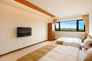 a bedroom with a large bed and a flat screen tv at Lo Hong ka Countryside House in Luodong