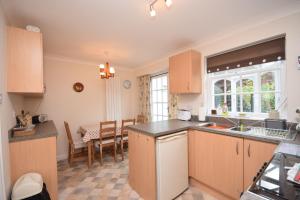 a kitchen with wooden cabinets and a dining room at Birch End, Midhurst in Midhurst
