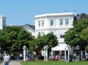 a white building with people sitting in front of it at Haus Elimar Weber in Norderney