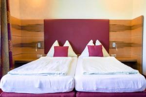 2 łóżka w pokoju hotelowym z białymi i czerwonymi poduszkami w obiekcie Fischwirtshaus Landmotel Die Donaurast w mieście Persenbeug