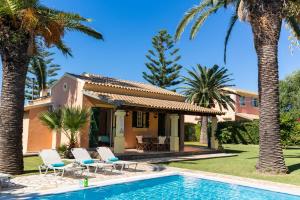 a villa with a swimming pool and palm trees at Villa Angelos in Acharavi