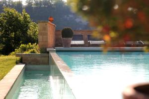 a swimming pool with some chairs next to it at Hôtel La Villa Romaine in Carsac-Aillac