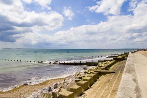 a beach with a pier and the ocean at Caedwalla House, Selsey in Selsey