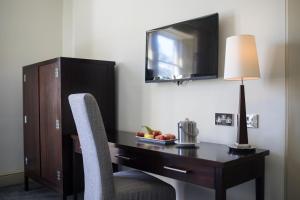 a desk in a hotel room with a television and a chair at Nether Abbey Hotel in North Berwick