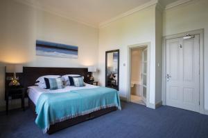 a bedroom with a large bed with a blue blanket at Nether Abbey Hotel in North Berwick
