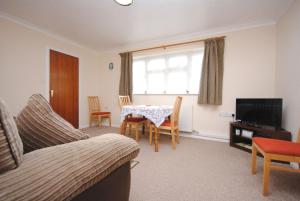 a living room with a table and chairs and a television at Cullimore, West Wittering in West Wittering