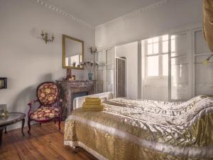 Petit Château في Laborde: غرفة نوم بسرير وكرسي ومرآة