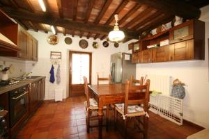 a kitchen with a wooden table and chairs in it at Casolare con Piscina al mare in Castagneto Carducci +17 photos