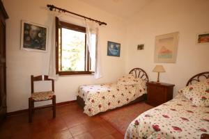 a bedroom with two beds and a chair and a window at Casolare con Piscina al mare in Castagneto Carducci
