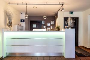 a lobby with a white counter with pictures on the wall at Hotel Wandinger Hof by Lehmann Hotels in Markt Schwaben