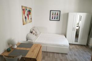 a white bedroom with a bed and a wooden table at Le Cocon de Cordeliers in Lyon