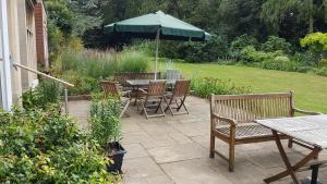 a patio with tables and chairs and an umbrella at Benslow Music Historic Stay in Hitchin in Hitchin