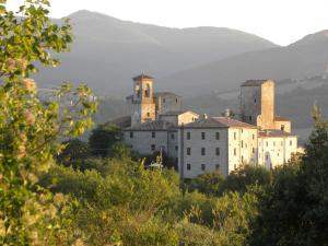 un grupo de edificios en una colina con montañas en el fondo en Castello Izzalini Todi Resort, en Todi