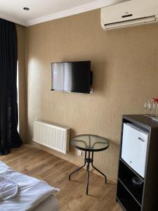 ein Hotelzimmer mit einem Tisch und einem TV an der Wand in der Unterkunft 7 Baits Hotel in Tbilisi City