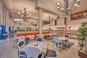 a restaurant with white tables and chairs and a bar at Sandos Papagayo in Playa Blanca
