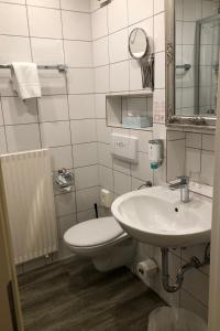 a bathroom with a white toilet and a sink at Landhotel Franck Garni in Brietlingen