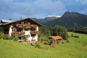 a house on a hill with mountains in the background at Landhaus Eggensberger in Fischen