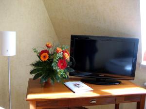 einen Fernseher mit einer Vase Blumen auf dem Tisch in der Unterkunft Altstadthotel Schex in Altötting