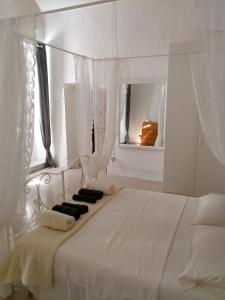 een witte slaapkamer met een wit bed en een spiegel bij Casa Giordano Bruno in Tarquinia