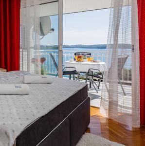 a bedroom with a bed and a balcony with a table at Adriatic Sea View Apartments in Trogir