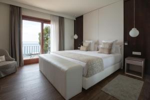 a bedroom with a large white bed and a balcony at Hotel Santa Marta in Lloret de Mar