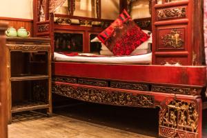 1 dormitorio con cama de madera y dosel rojo en Pingyao Hongyuyuan Guesthouse en Pingyao